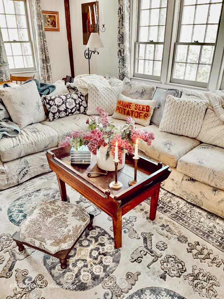 Living room vintage inspired decorated for spring with vintage crock full of lilacs.