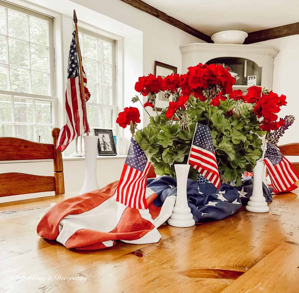 Red geraniums, flags dining room centerpiece.