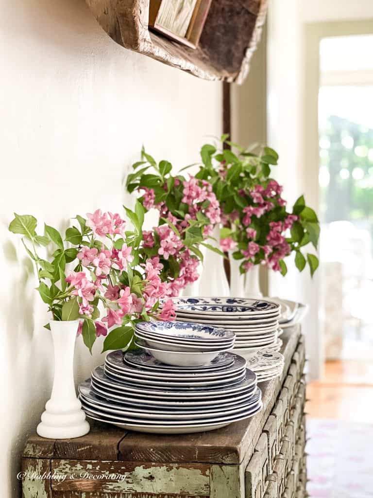 5 Clever Ways to Decorate with Yard Sale Finds.  Stack of dishes and pink flowers.