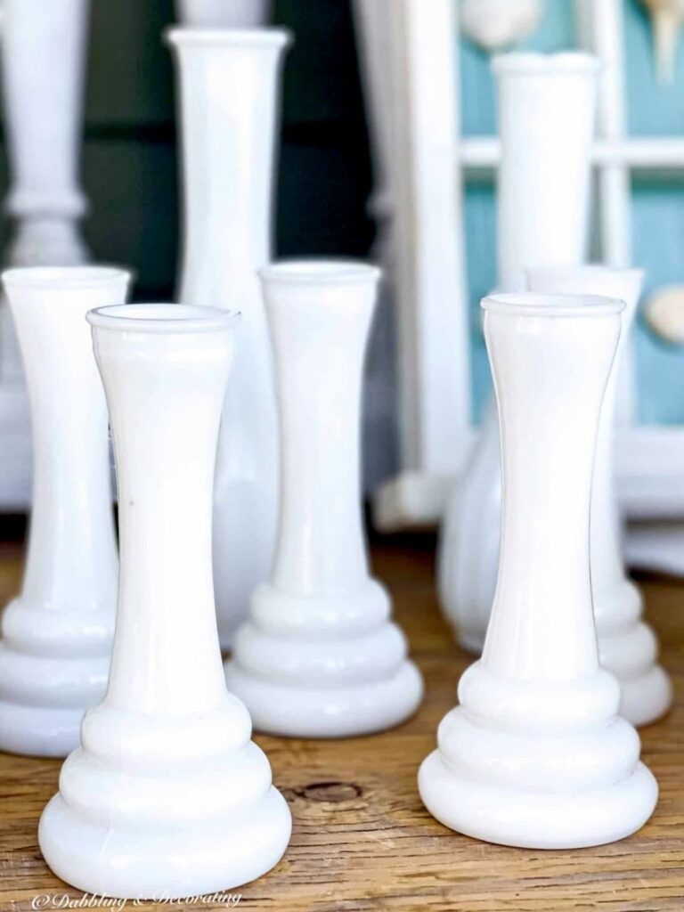 7 Milk glass vases on shelf at antique store.