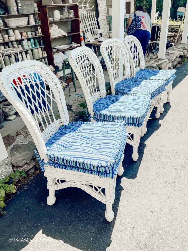 four white wicker vintage chairs with blue cushions at antique store.