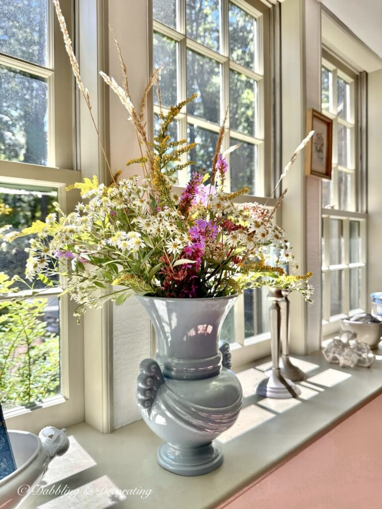 Late summer wildflower arrangement in vintage blue vase on sunny windowsill in antique Maine home.