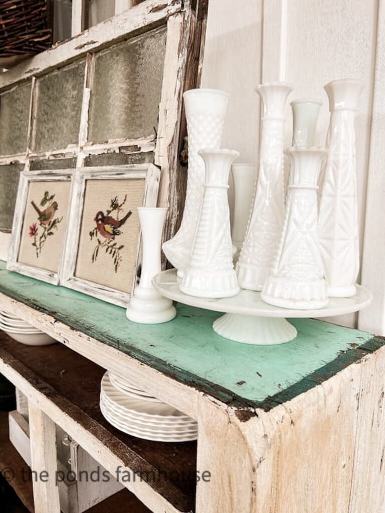 Vintage milk glass vases on milk glass cake stand on counter shelf.