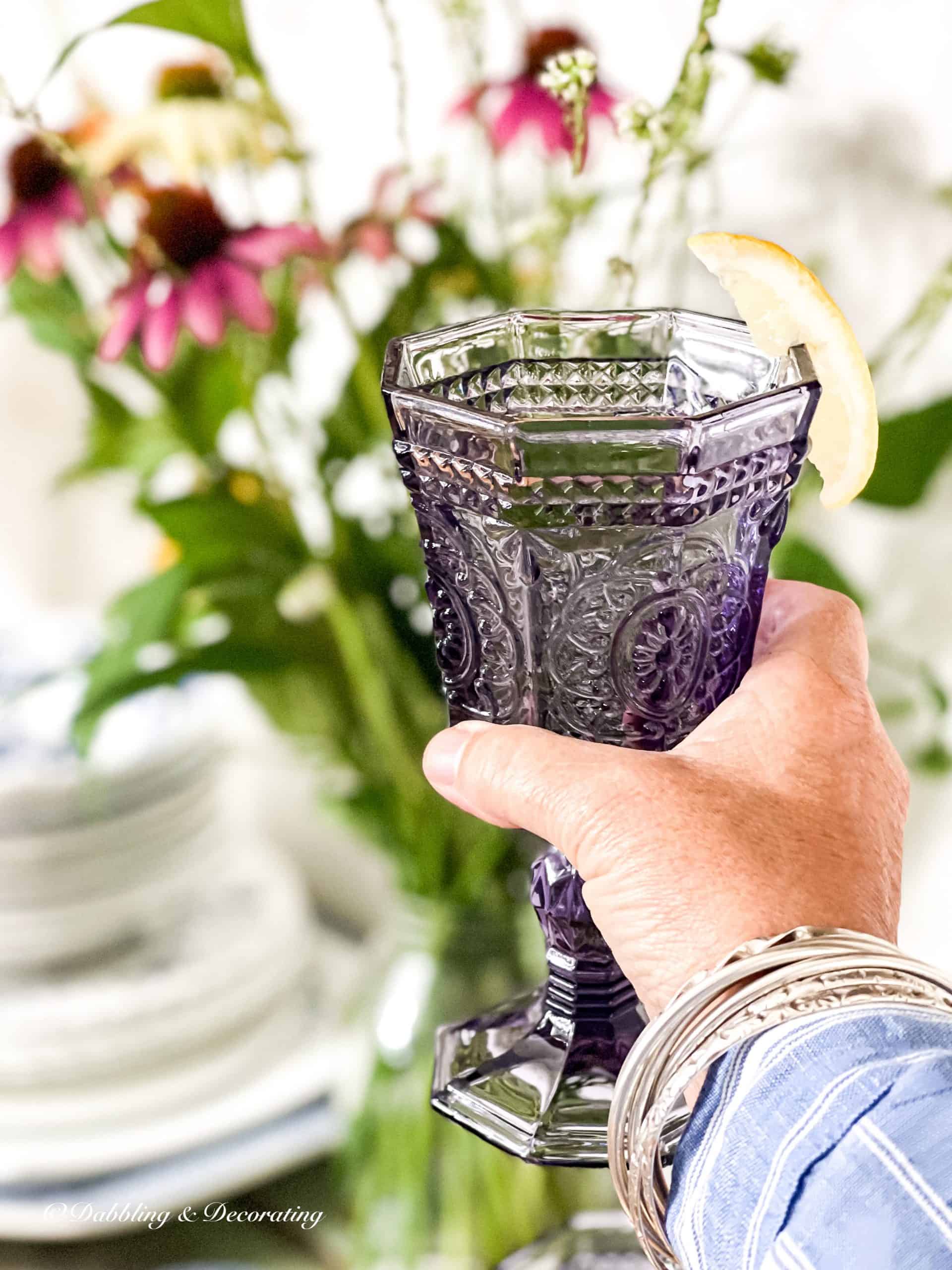 Antique amethyst glassware cheers in hand with lemon.