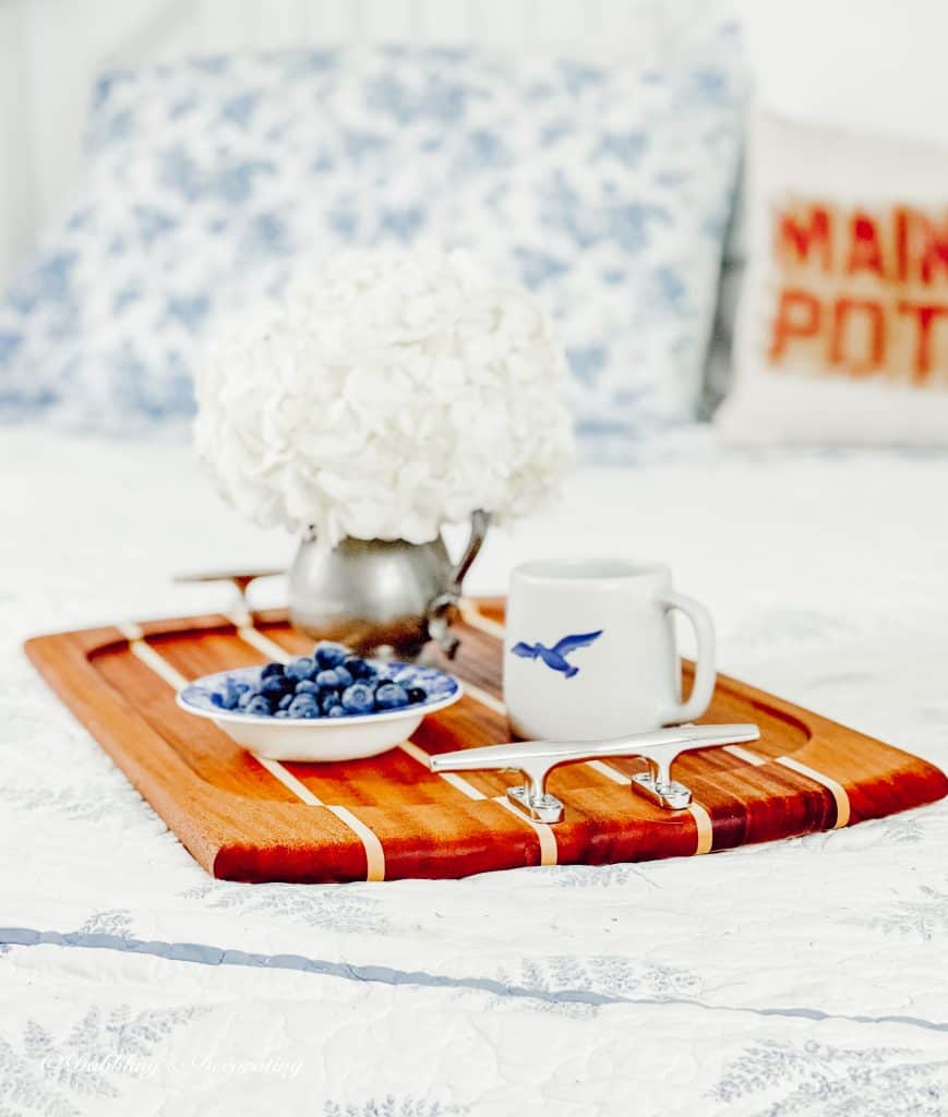 A thrifty wooden tray decorated with fresh blueberries and a cozy mug on a bed, creating charming home decor.