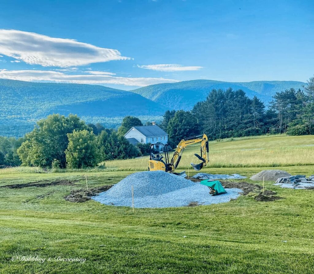 Bulldozer with large pile of stone in backyard with mountains in the background.
