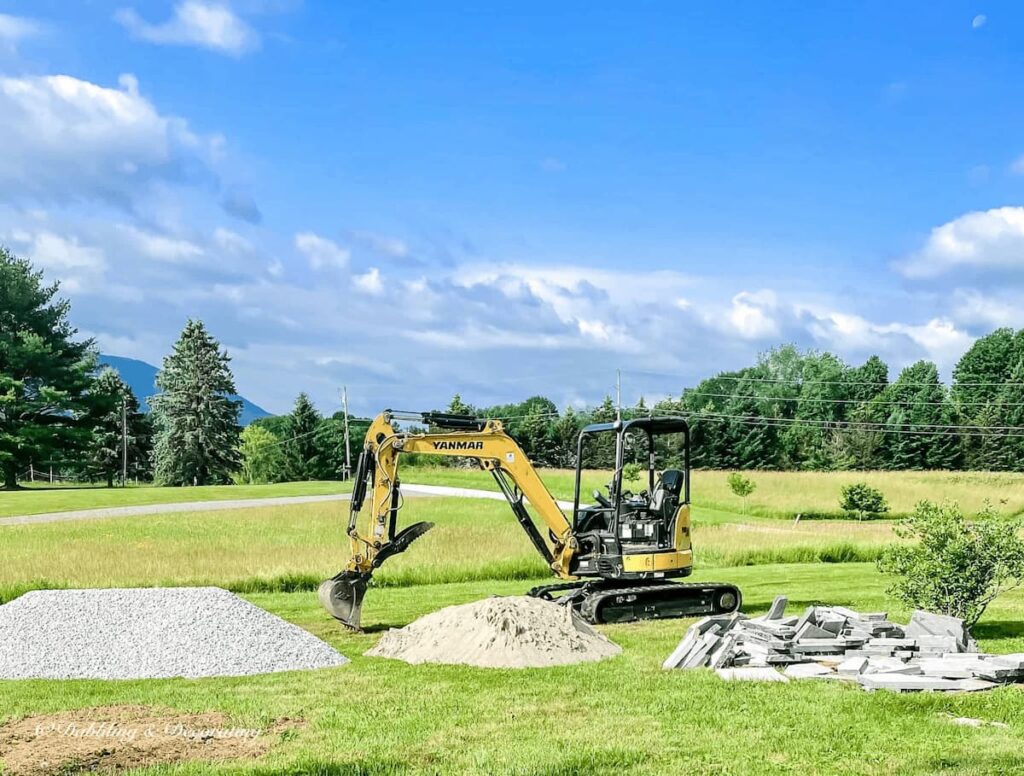 Bulldozer in backyard with all the materials needed to create an outdoor round patio.