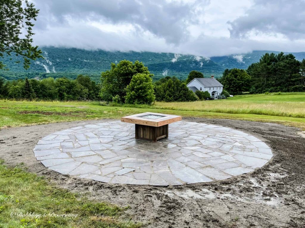 GreatOutdoor fire pit placed in the middle of new round patio in backyard in the mountains, nearly completed.