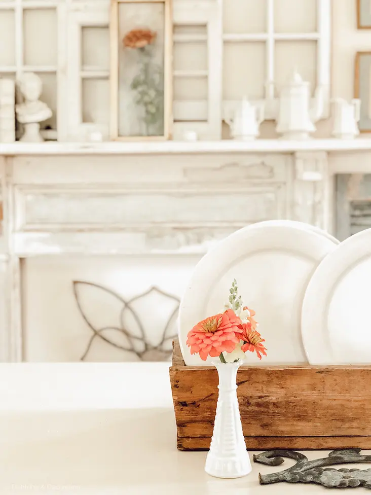 A vintage wooden crate adorned with flowers serves as a charming home decor piece, placed elegantly on a table in front of a cozy fireplace.