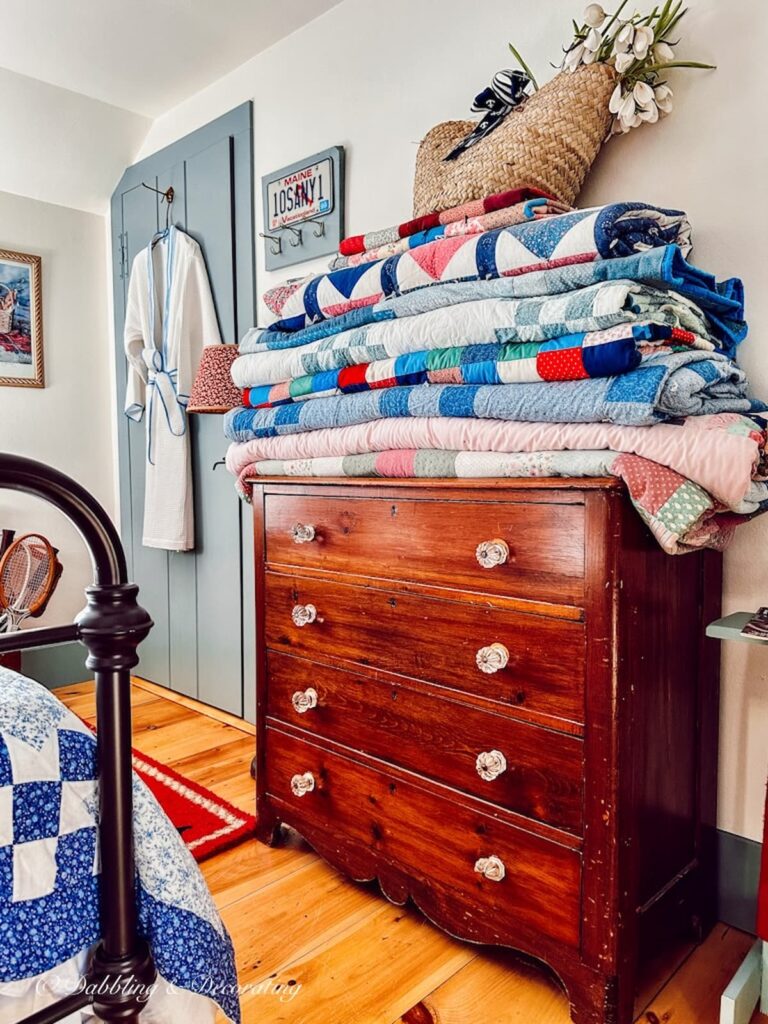 Heirloom homemade quilts folded and gathered on a bedroom dresser.