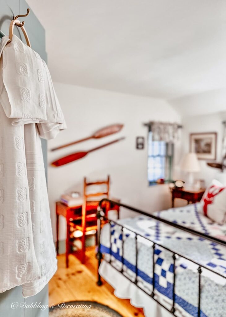 White quilt hanging from embroidery hook on bedroom door.