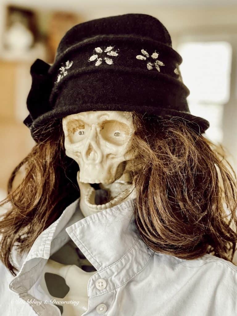 Halloween skeleton decorated as a woman with a wig and hat.