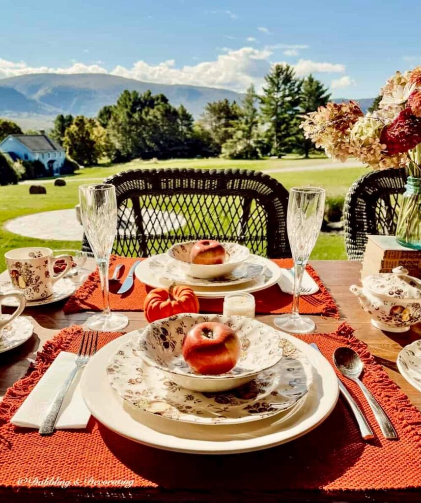 Autumn themed dinnerware on outdoor porch tablescape with mountain views.