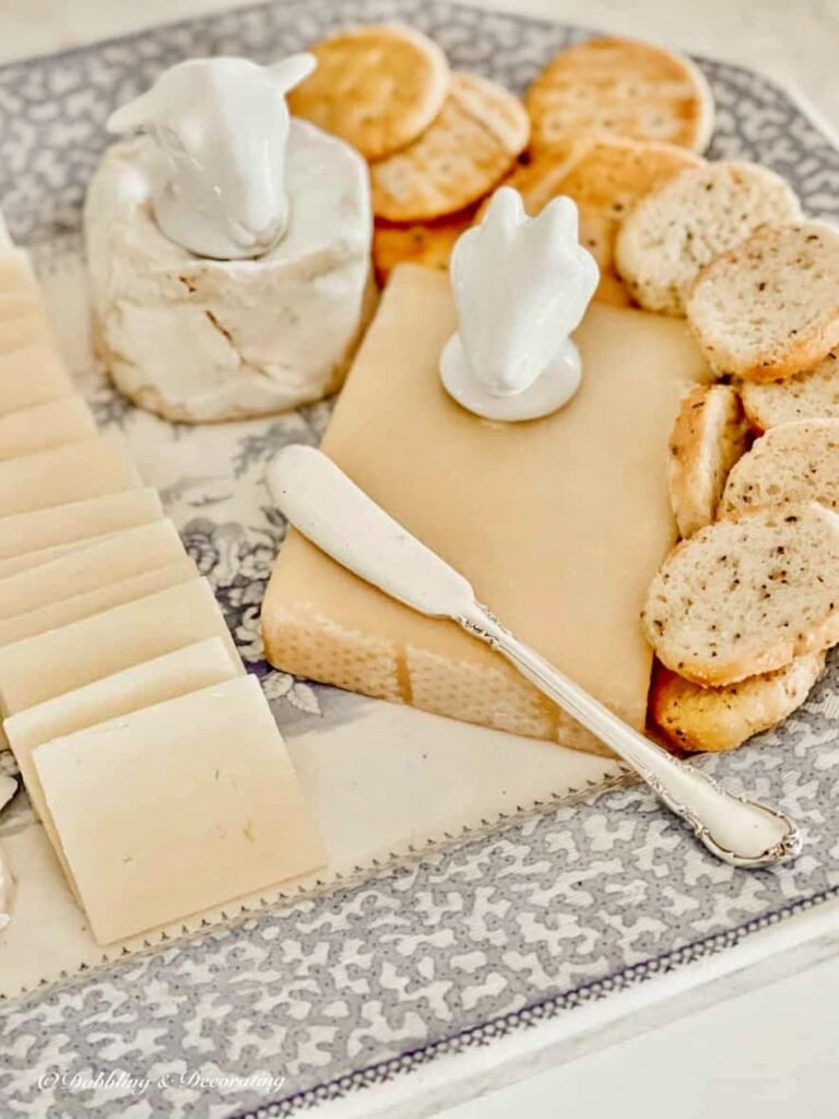 Vintage platter with cheeses, crackers and cheese holders with sterling silver cheese knife on vintage platter.