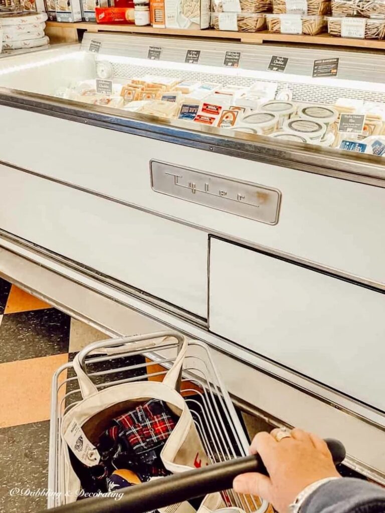 Large shop refrigerator filled with cheese and small Vermont Country Store shopping basket.