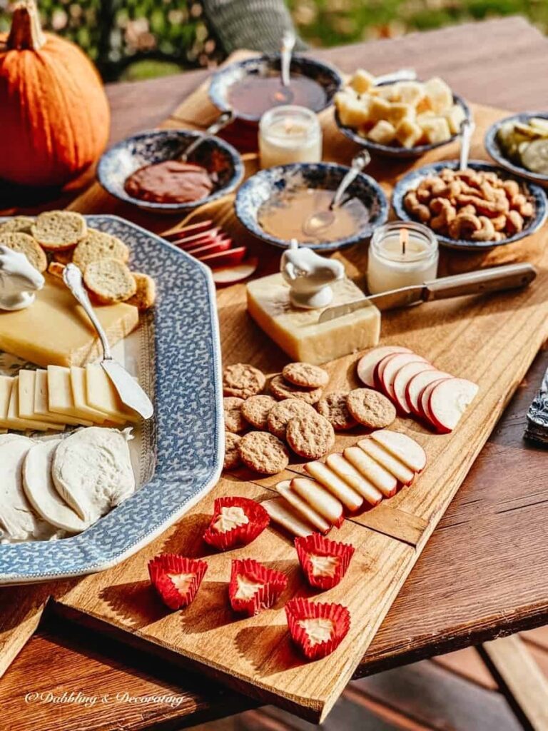 Vermont style vintage cheese board and platter with pumpkins on fall porch table.
