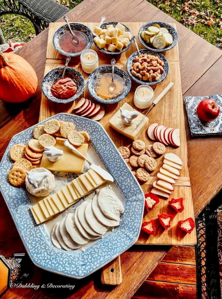 Vintage style cheese board and platter with Vermont cheeses and pumpkin on fall porch table.