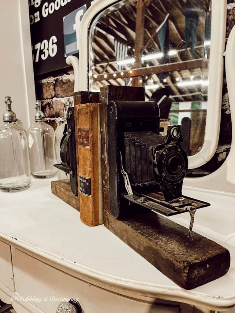 Antique cameras as bookends with old books on shelf.
