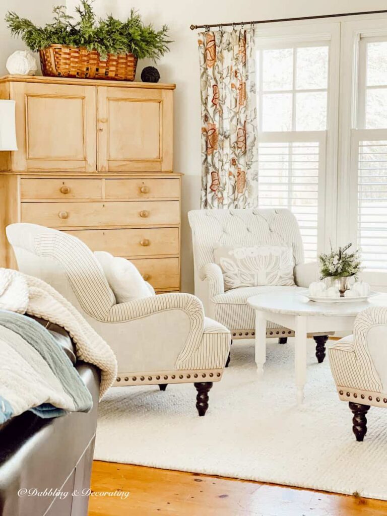 Sitting room with a neutral color palette cozy with white rug and marble coffee table and vintage pine hutch decor.