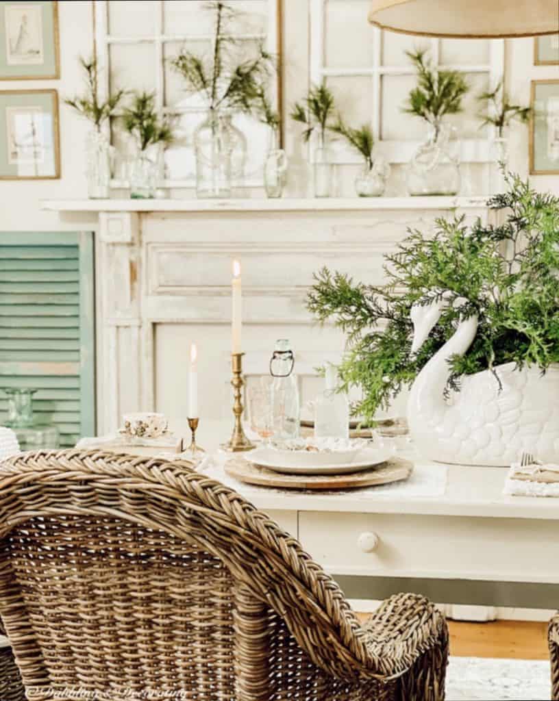 Farmhouse Dining Room Table Set with Greenery and Vintage Bottles for Winter.