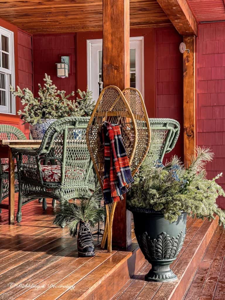 DIY plastic urn planter with evergreens with snowshoes on winter porch.
