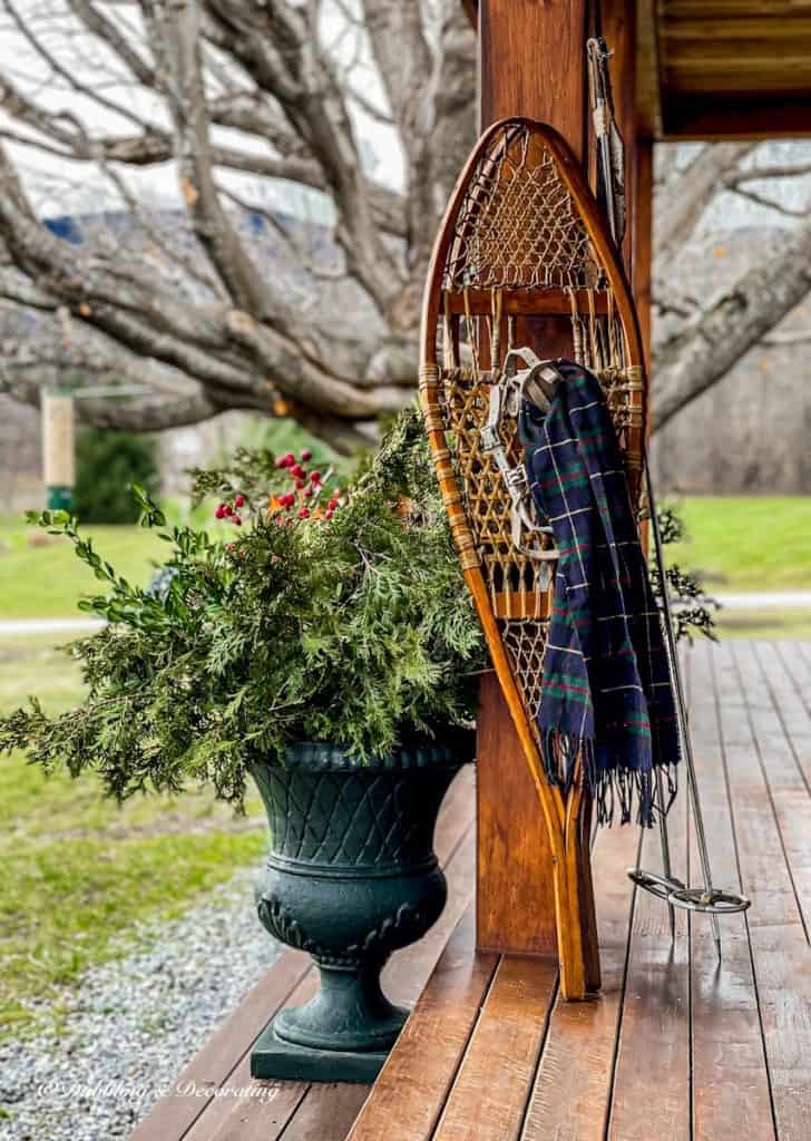 Antique snowshoes with tartan scarf on winter porch with planter of evergreens for the holidays.