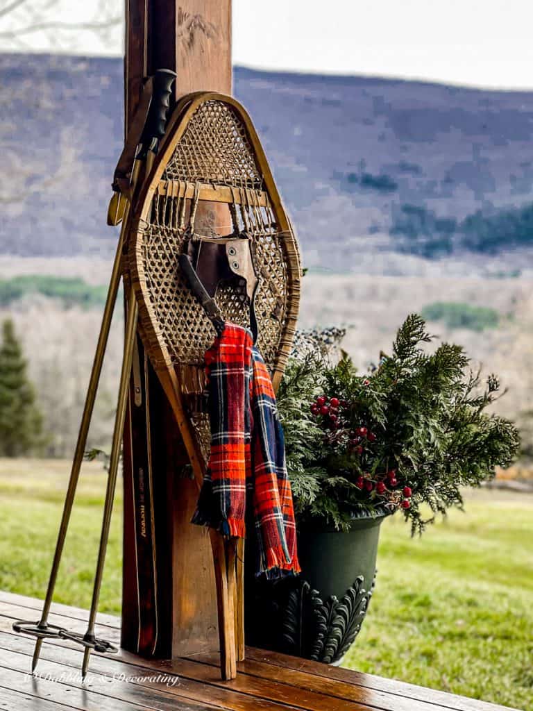 Red and blue plaid scarf on antique snowshoes on winter porch.
