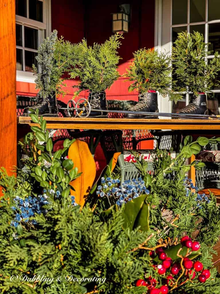 Vintage Ski Boots decorated in antique Christmas decor on front porch with evergreens.