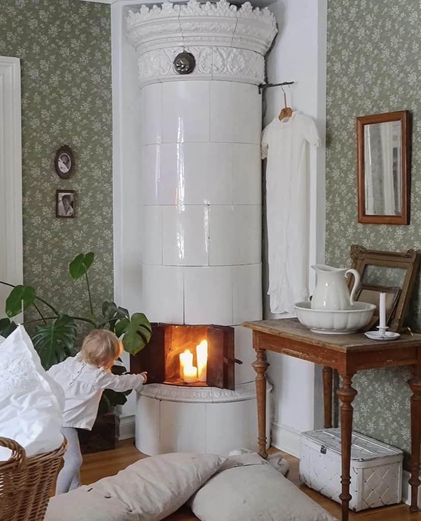 Little girl next to large white fireplace in homes in Sweden.