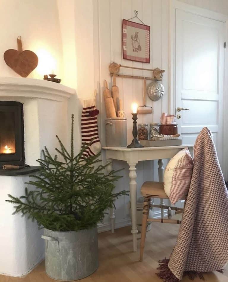 Christmas tree in galvanized bucket net to fireplace in Swedish home living room.
