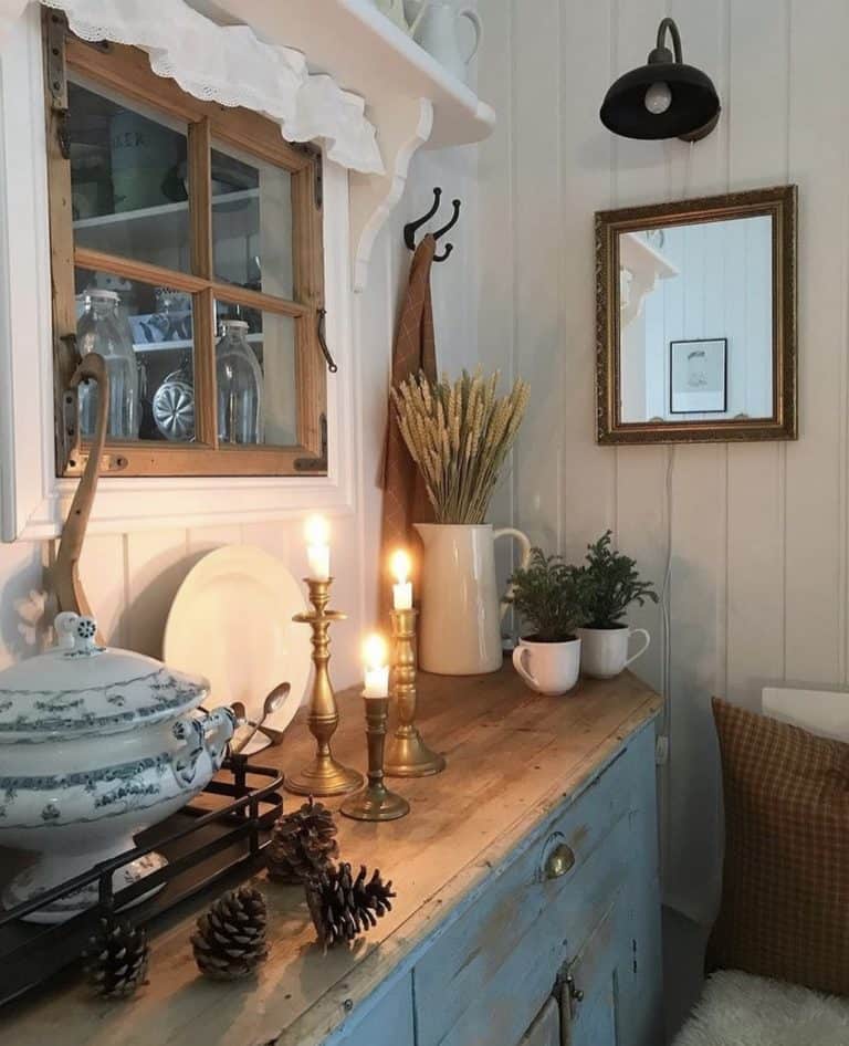 Cozy Swedish home interior with lit candles, and cozy details on vintage cabinet.
