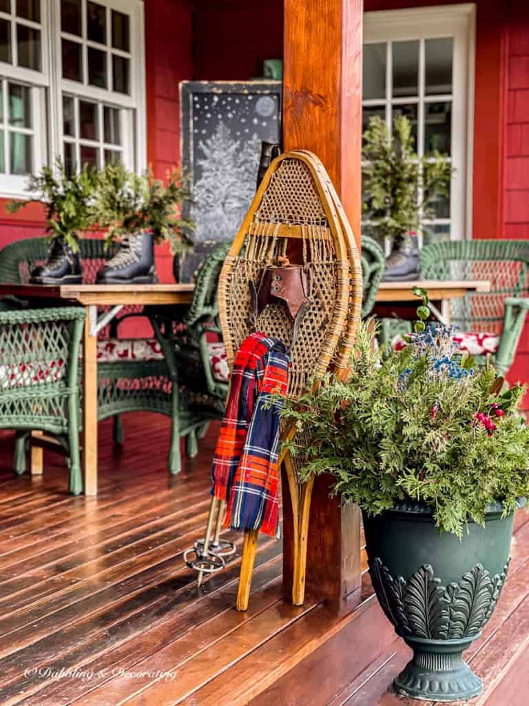Vintage ski lodge decor with snowshoes, evergreens on winter porch.