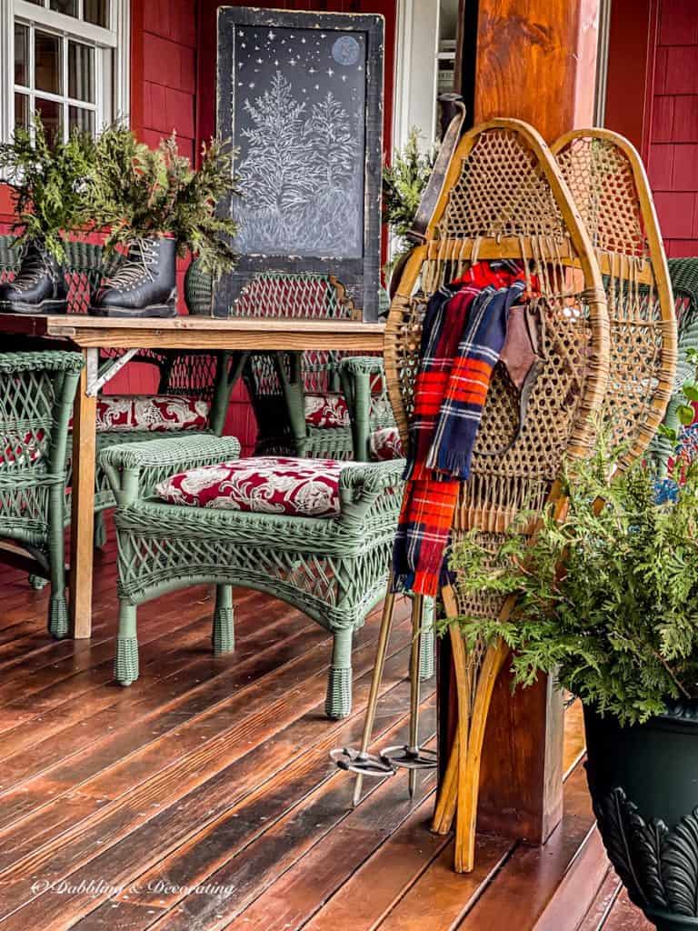 Vintage snowshoes decorated with a red scarf on winter porch.