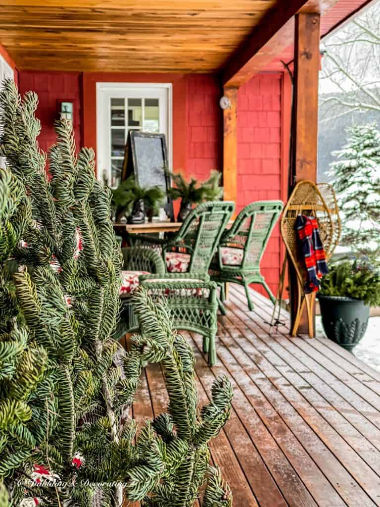Vintage winter porch with evergreens, snow and vintage ski lodge decor.