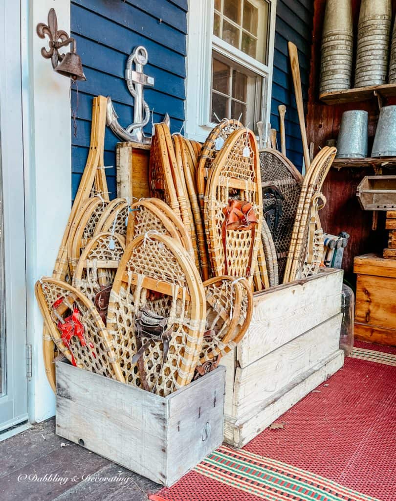 Crates of vintage wooden snowshoes on antique store outdoor porch.