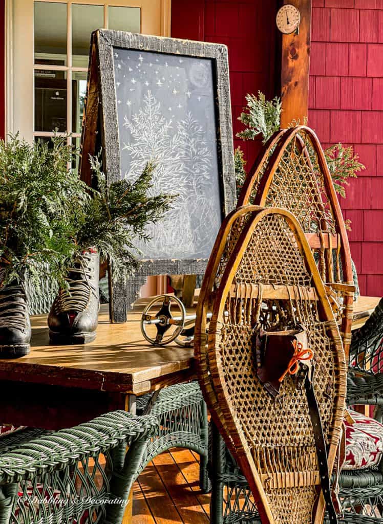 Wooden snowshoes with vintage ski boots, poles and chalkboard on porch.
