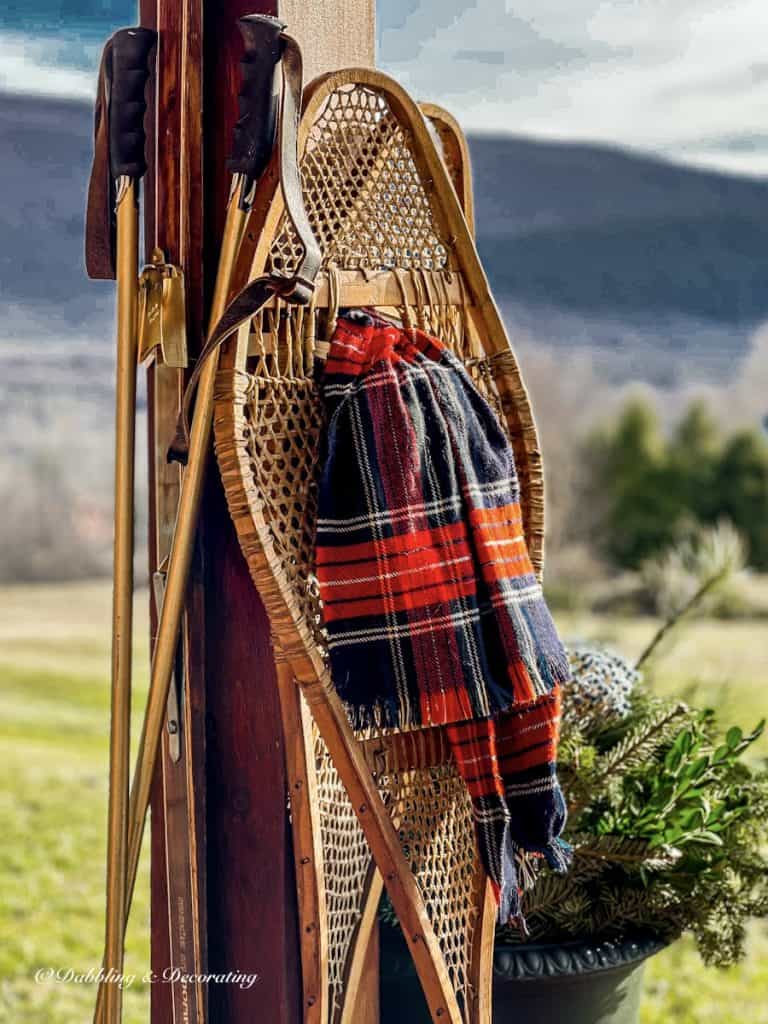 Vintage wooden snowshoes on porch beam with red scarf and vintage ski poles in the mountains.