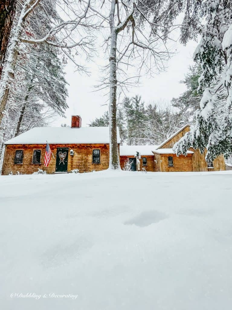 Cedar Shake Siding home in coastal Maine with a blanket of snow and USA Flag.