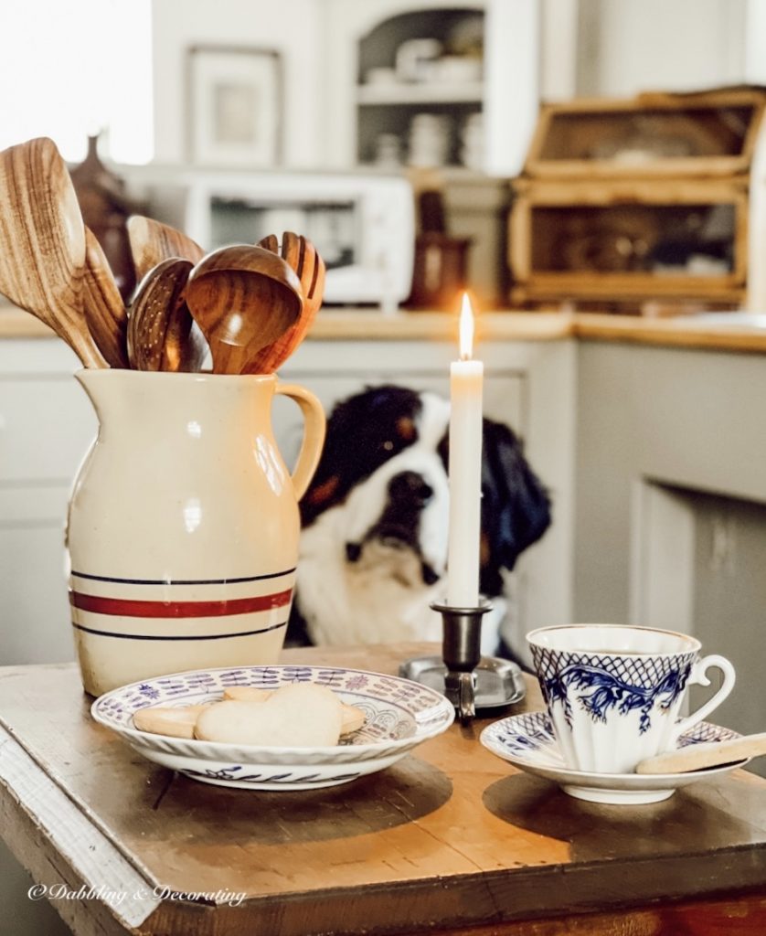 Vintage kitchen decor ideas in center kitchen table with crockery and candle and dog looking on.