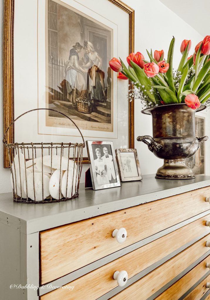 Vintage Hutch decorated with pictures, flowers, and a basket of sand dollars.