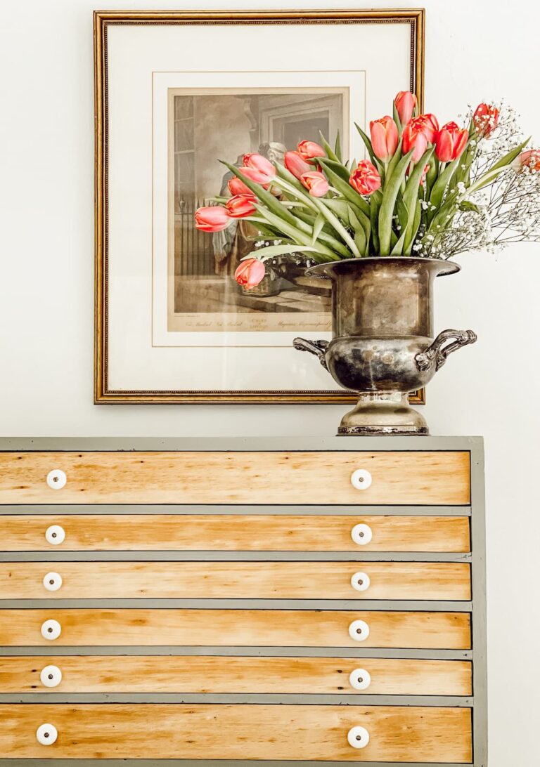 Vintage hutch with plentiful small drawers with bouquet of pink tulips in silver champagne bucket Vintage hutch styling ideas.