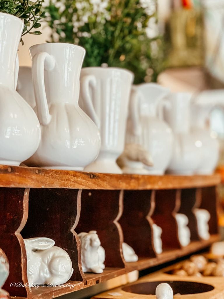 Vintage white vases on wooden shelving in secondhand shop.