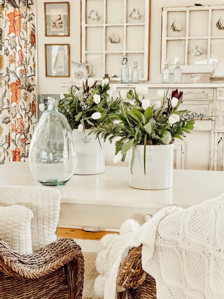 White Tulips and Greenery in Vintage Crocks on Farmhouse Table.