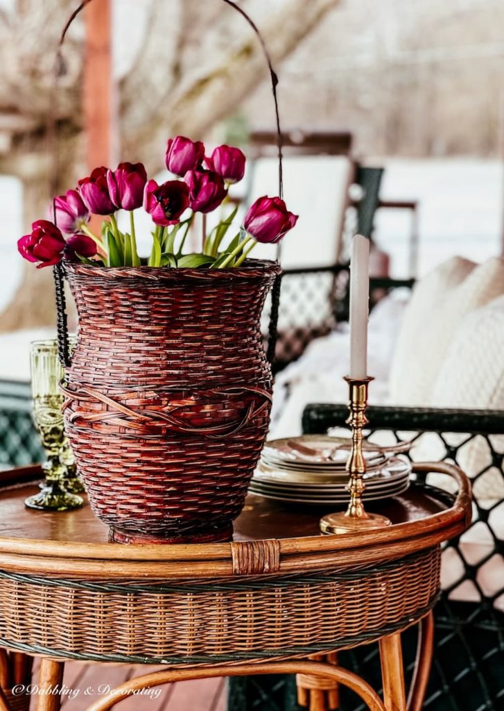 Pink tulips in wicker back on back porch wicker table.