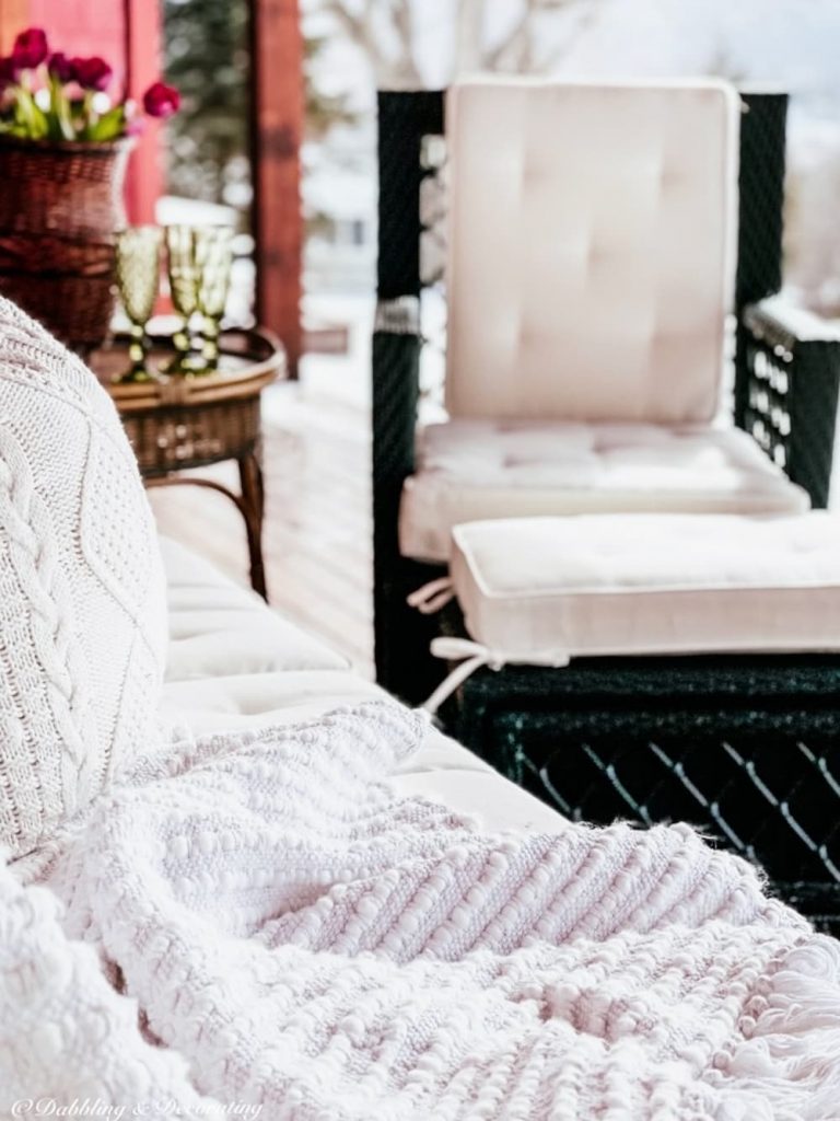 White cushions on evergreen wicker furniture on back porch.