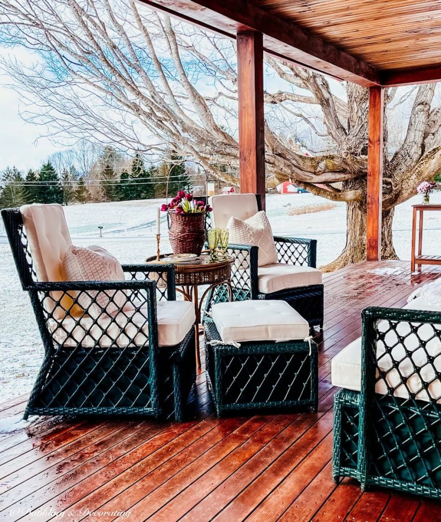 Back porch with snow and wicker furniture set.