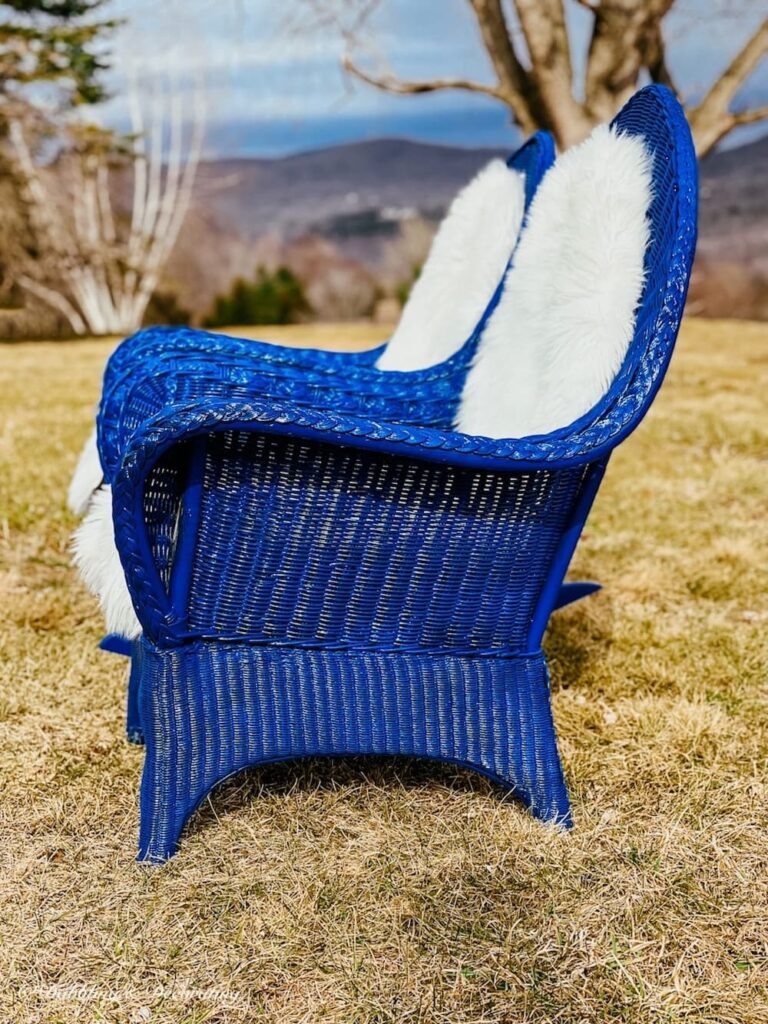 Two blue wicker chairs with white sheepskins on outdoor lawn in how to paint wicker furniture.