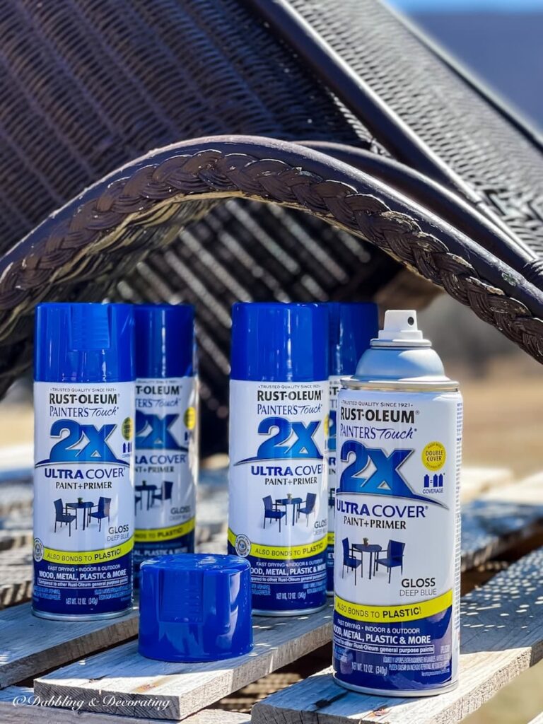 Four cans of blue spray paint for how to paint wicker furniture.