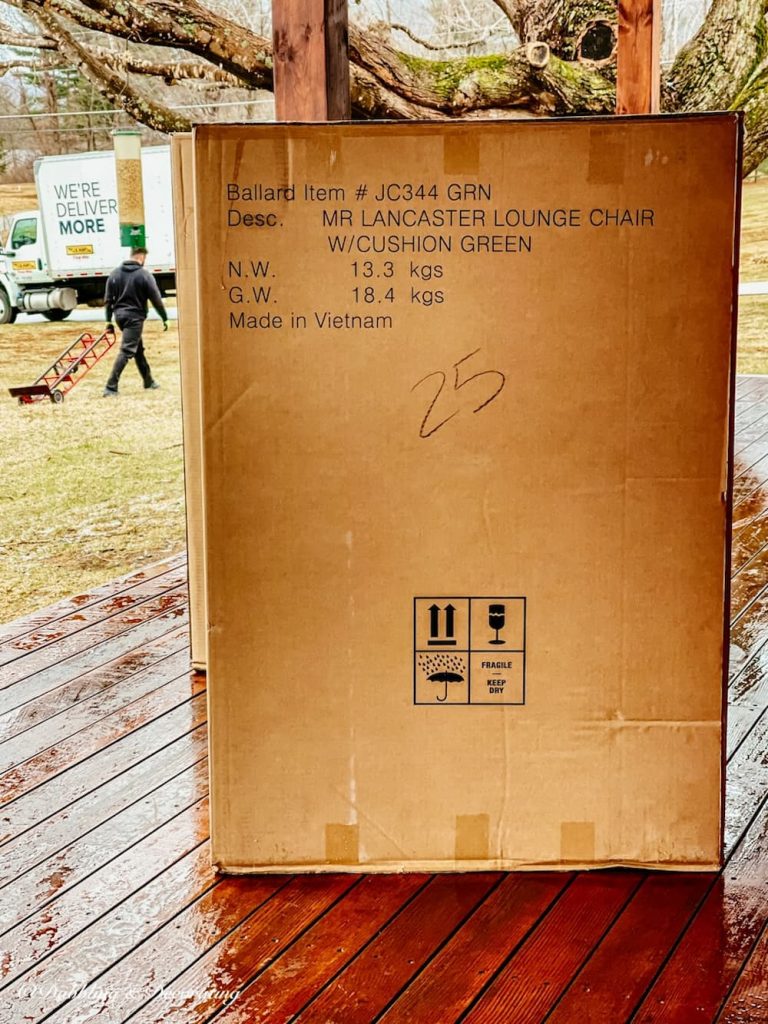 Boxed wicker furniture on front porch with delivery man and truck.