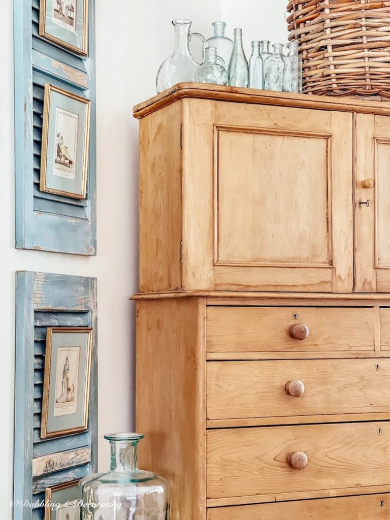 A thrifty décor featuring an old dresser with blue shutters and wicker baskets.